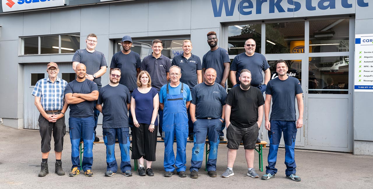 Das komplette Team der Garage Jost GmbH hinter einem hellblauen SAAB.
